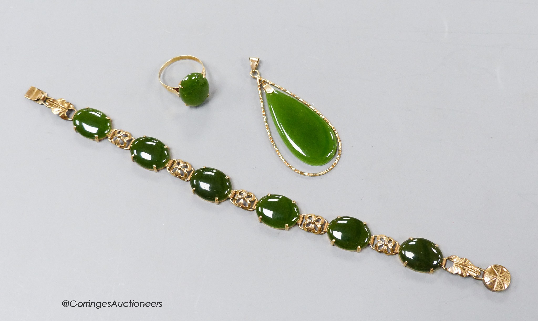 A 14k yellow metal and cabochon jade set bracelet, 18.5cm, gross 13.3 grams, an 18k mounted jade pendant and dress ring, gross 8.5 grams.